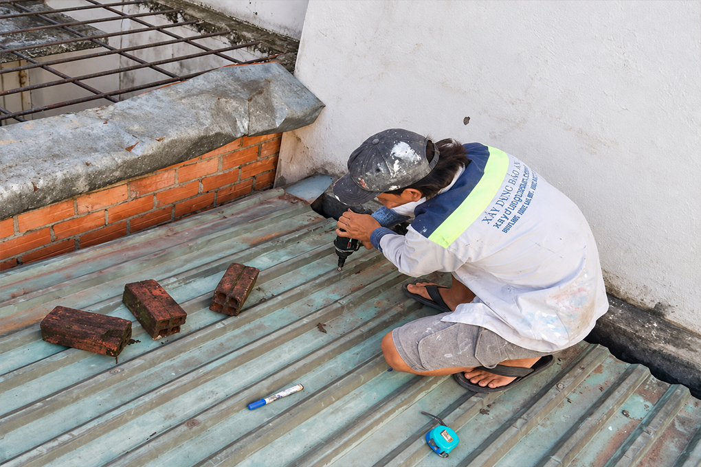Mái tôn dột tại vít: Nguyên nhân và cách xử lý 2 Mái tôn màu xanh cạnh tường nhà và đường máng thu nước